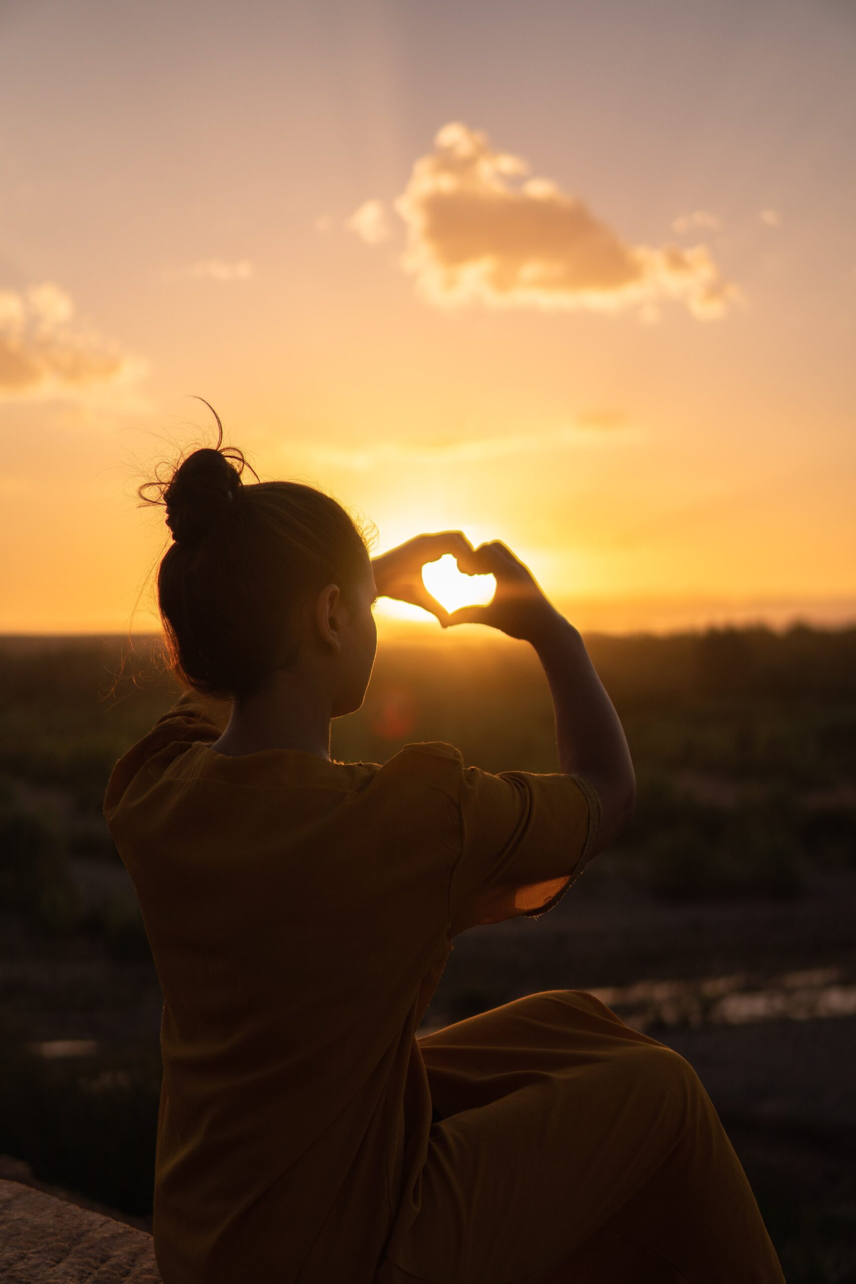 forming a heart with hands near the sunset