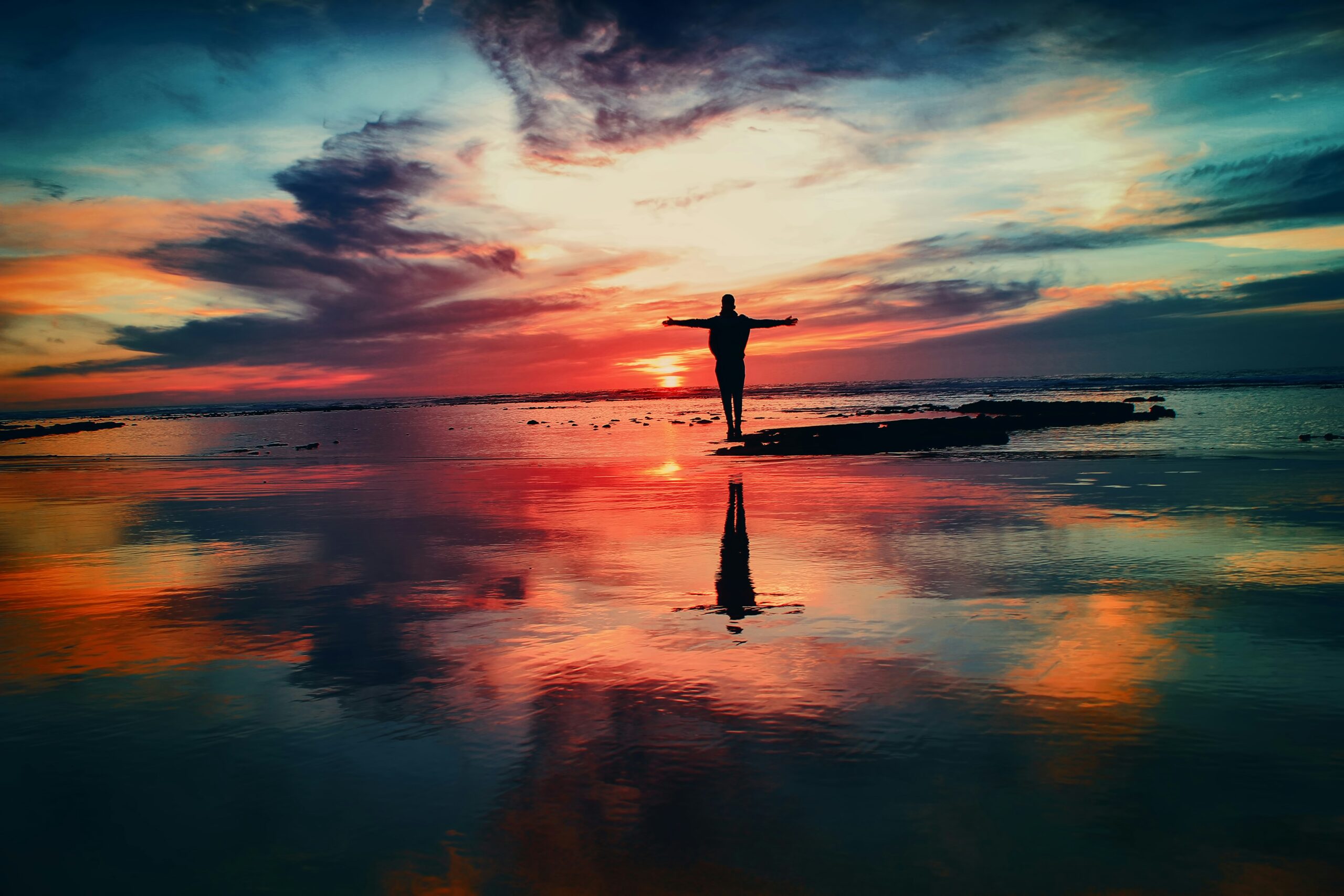 person standing underneath a colorful sunset