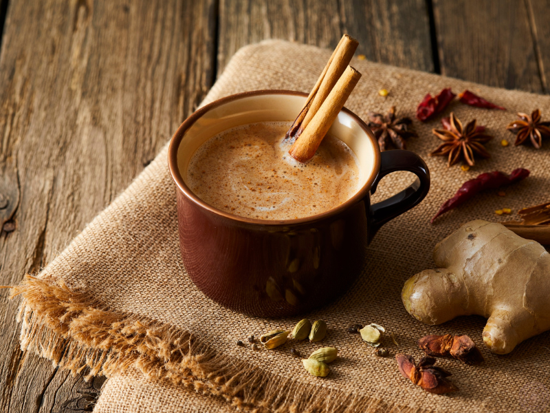 A mug of herbal tea with cinnamon sticks and ginger placed on a soft muslin cloth, symbolizing Ayurvedic remedies and daily rituals.