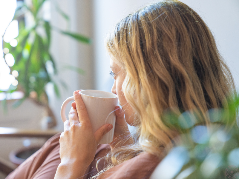 A close-up of a woman sipping tea from a mug, offering a sense of comfort, self-soothing, and gentle presence in moments of anxiety or fear.