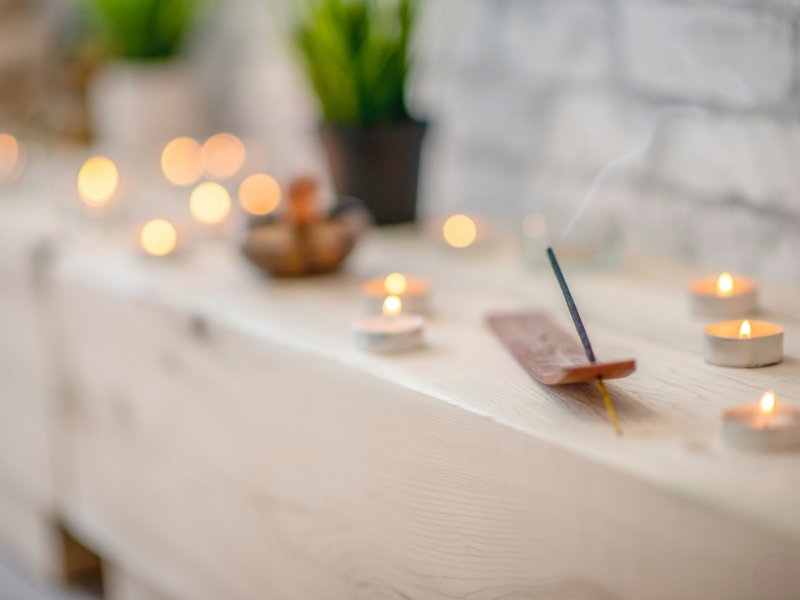 Incense burning on a ledge surrounded by tealight candles, illustrating a meditative atmosphere that supports inquiry into the illusory layers of the mind.