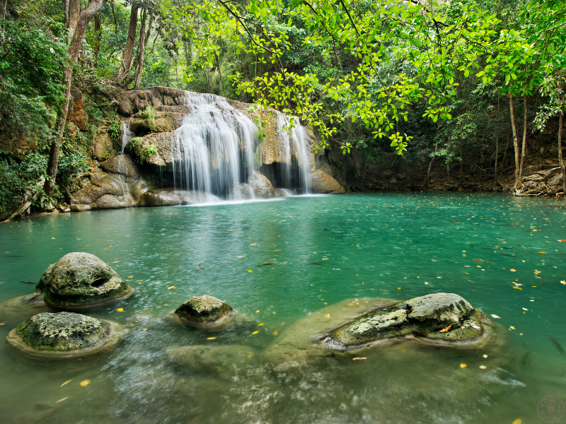 A flowing waterfall cascading into turquoise-colored water. 