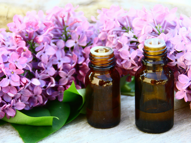 Two essential oil bottles with lilac flowers in the background, evoking feelings of comfort and emotional uplift.