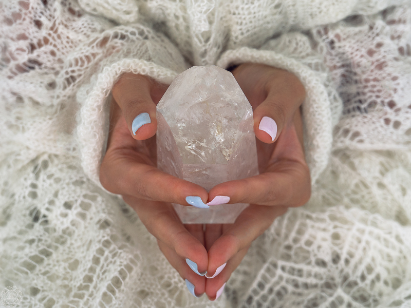 Close-up of a woman’s hands holding a clear crystal, symbolizing clarity and spiritual awakening.