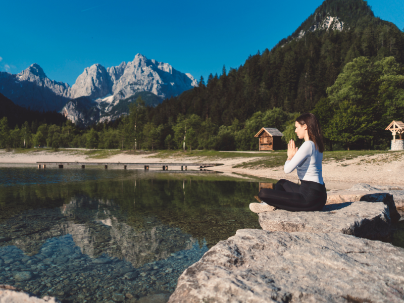 Woman meditating peacefully in nature, symbolizing awareness and freedom from the pain-body.