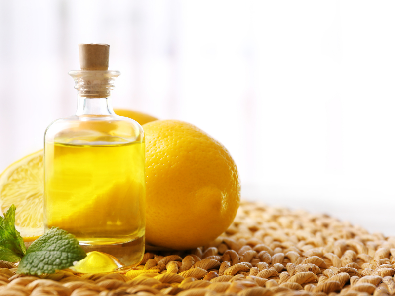 Close up of an essential oil bottle with fresh lemons in the background, symbolizing citrus oils’ energizing and mood-boosting benefits.