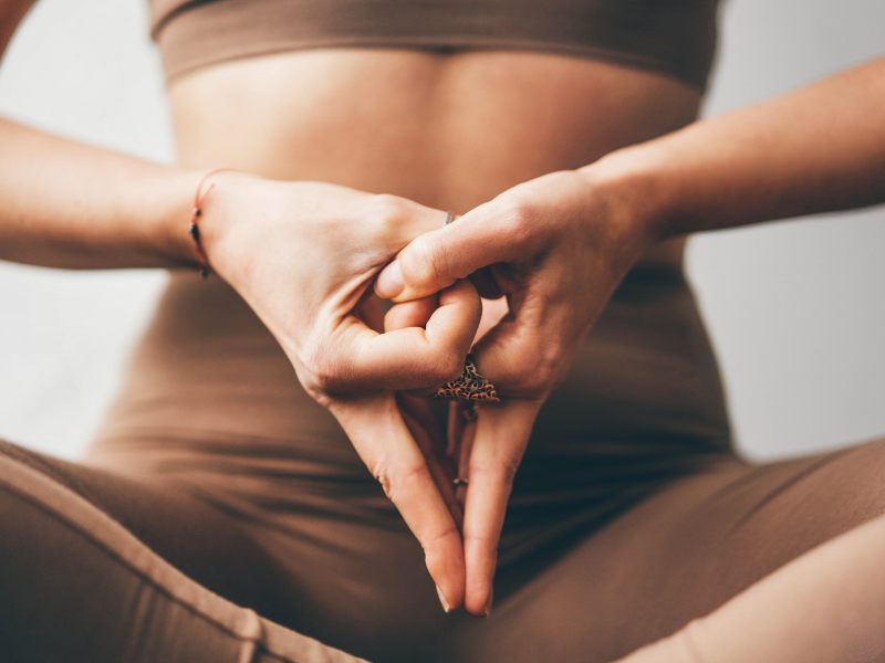 Close up of a woman’s hands in yoni mudra, representing stillness, creation, and grounding energy.