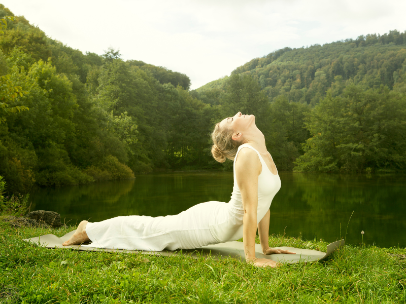 Woman practicing yoga asana in a lush green park, reflecting the harmony between body, breath, and awareness.