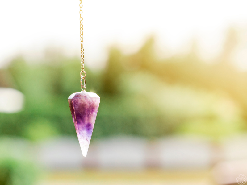 Close-up of a purple crystal pendulum representing intuitive awareness and the movement of energy within the pendulum of duality.