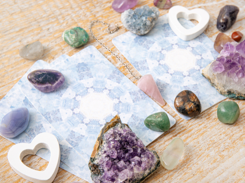 Tarot cards surrounded by crystals with a rose quartz pendulum in the center, symbolizing self-reflection, guidance, and navigating the pendulum of duality.